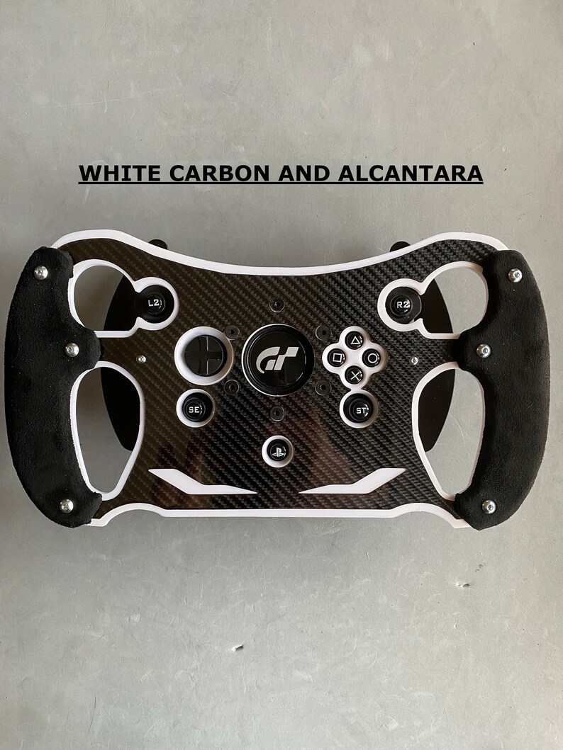 May include: A black and white racing steering wheel with a carbon fiber design and white accents. The steering wheel has a PlayStation button and a GT logo in the center.