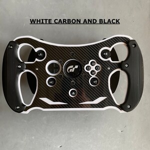 May include: A black and white racing steering wheel with a carbon fiber design and the text "GT" in the center. The steering wheel has buttons and paddles for gaming.