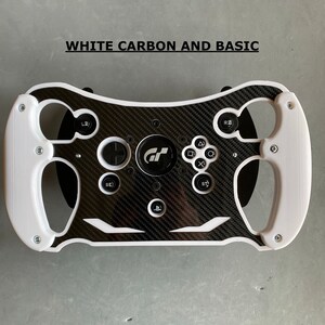 May include: White racing steering wheel with a carbon fiber design and black buttons. The steering wheel has a GT logo in the center.