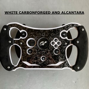 May include: A white racing steering wheel with black accents and a carbon fiber design. The steering wheel has a PlayStation logo and the text "GT" in the center. The text "WHITE CARBONFORGED AND ALCANTARA" is visible at the top of the image.