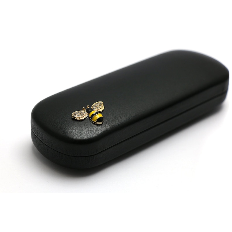 May include: Black leather glasses case with a gold bee design. The bee has black and yellow stripes and clear rhinestones.