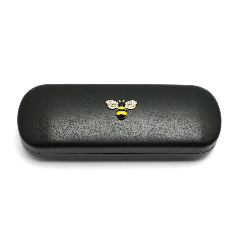 May include: Black leather glasses case with a gold bee design. The bee has yellow and black stripes and clear rhinestones.