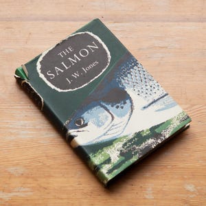 May include: A book titled "The Salmon" by J.W. Jones, with a green cover and a fish illustration in blue and white. The book is on a light brown wooden surface.