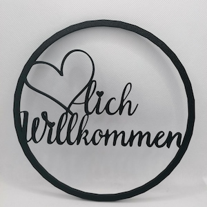 Könnte beinhalten: Schwarzer Holz-Kreis mit den Worten "Herzlich Willkommen" und einem Herz-Ausschnitt.