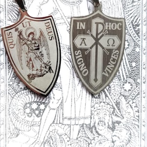 May include: Two silver pendants, one with a depiction of an angel and the text "QUIS UT DEUS" and the other with a cross and the text "IN HOC SIGNO VINCES".