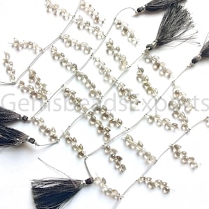 May include: A strand of smoky quartz gemstone beads with silver wire and black tassels. The beads are faceted and have a teardrop shape.