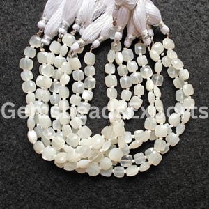 Puede incluir: Múltiples hilos de cuentas de piedras preciosas de corte cuadrado en blanco roto con detalles de borlas blancas. Las cuentas están ensartadas, creando un efecto en capas. La imagen tiene el texto "Gemsheads Exports".