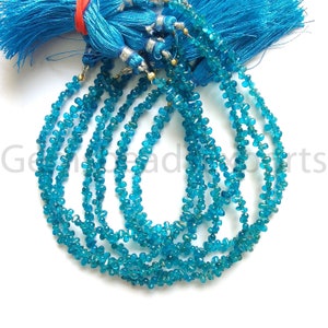 May include: Strands of small, irregular, turquoise-colored gemstones are displayed. The gemstones are strung together, forming multiple necklaces. A blue tassel is visible at the top, adding a decorative element. The gemstones appear to be natural and have a polished finish.