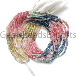 May include: A collection of gemstone bead strands in a variety of colours, including pink, blue, yellow, and green. The small, faceted beads have a subtle shimmer. White tassels secure the strands. The image includes the text "GemsGoodsExports".