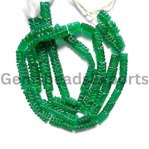May include: Strands of vibrant green gemstone beads, each carved with a leaf design. The beads are strung together, with a white tassel at one end. The beads are a bright, translucent green color.