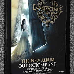 Peut inclure: Une affiche promotionnelle encadrée pour l'album The Open Door d'Evanescence, montrant une personne en robe longue devant une grande porte ouverte. Le texte indique The New Album Out October 2nd, Call Me When You're Sober et Woolworths.