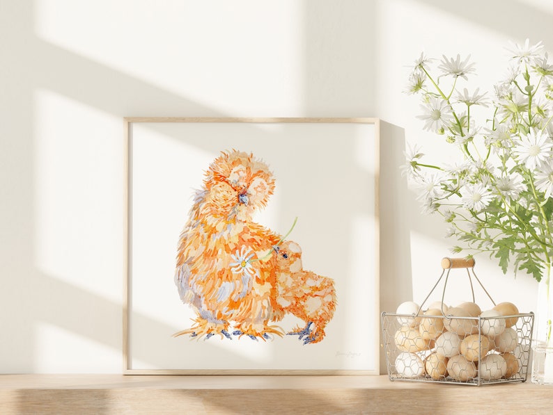 The print of the silkie chicken hen and chick has been framed, and displayed next to a basket of eggs and white daisies in a bright sunny kitchen.