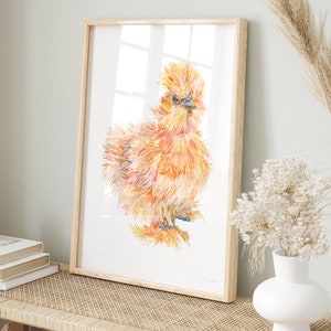 A print of a watercolour illustration of a buff orange coloured silkie chicken chick framed in a bright farmhouse entryway.