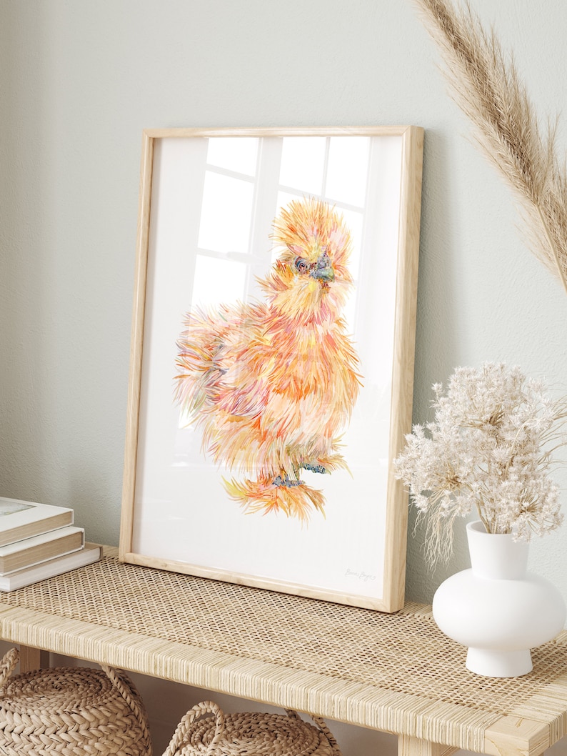 A print of a watercolour illustration of a buff orange coloured silkie chicken chick framed in a bright farmhouse entryway.