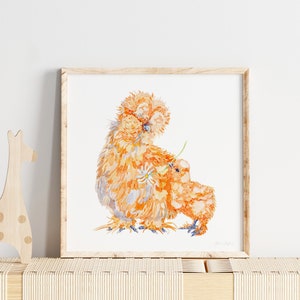 The print of the two orange silkie chickens is framed in a playroom, or nursery next to wooden toys.