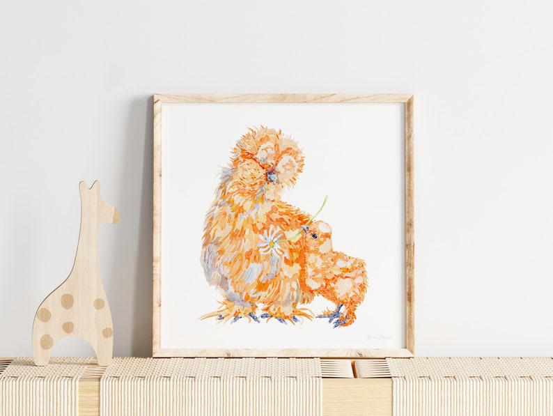 The print of the two orange silkie chickens is framed in a playroom, or nursery next to wooden toys.