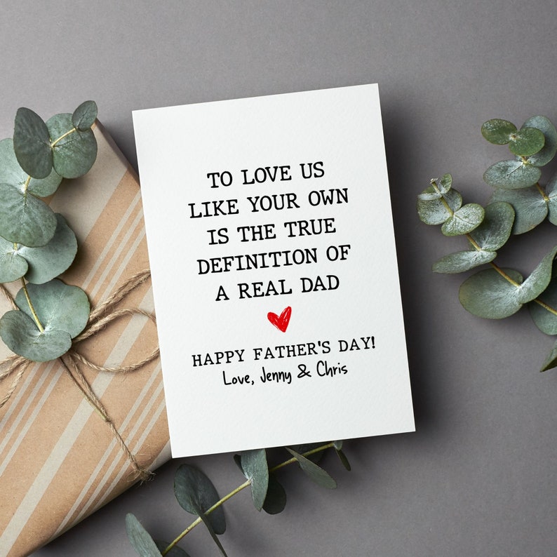May include: A white card with black text that reads "To love us like your own is the true definition of a real dad." A red heart is drawn below the text. The card also says "Happy Father's Day! Love, Jenny & Chris".