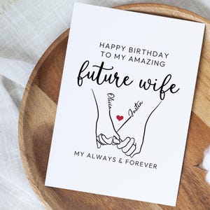 Może przedstawiać: Biała kartka z życzeniami z czarnym napisem "HAPPY BIRTHDAY TO MY AMAZING future wife". Przedstawia rysunek dw&oacute;ch splecionych dłoni z imionami "Olivia" i "Justin" oraz czerwonym sercem.