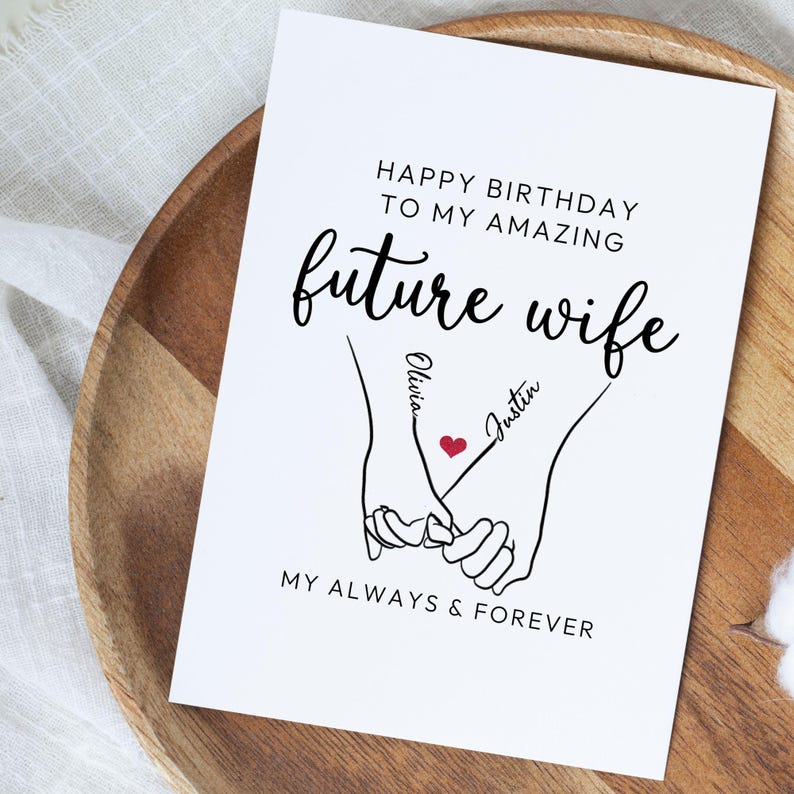 Może przedstawiać: Biała kartka z życzeniami z czarnym napisem "HAPPY BIRTHDAY TO MY AMAZING future wife". Przedstawia rysunek dw&oacute;ch splecionych dłoni z imionami "Olivia" i "Justin" oraz czerwonym sercem.