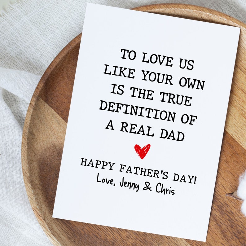 May include: A white card with black text that reads "To love us like your own is the true definition of a real dad. Happy Father's Day! Love, Jenny & Chris". A red heart is drawn above the text "Happy Father's Day!"