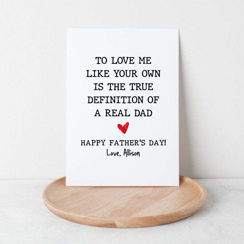May include: A white card with black text that reads "To love me like your own is the true definition of a real dad. Happy Father's Day! Love, Allison". A red heart is drawn above the text "Happy Father's Day!"
