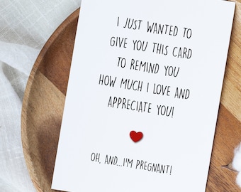 May include: A white greeting card with black text that reads, "I just wanted to give you this card to remind you how much I love and appreciate you! Oh, and...I'm pregnant!" A small red heart is affixed to the card.