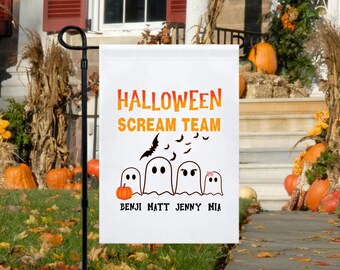 May include: A white Halloween garden flag with the words "HALLOWEEN SCREAM TEAM" in orange and yellow. Below are four ghost figures, a pumpkin, and the names BENJI MATT JENNY MIA. Black bats fly above the ghosts.