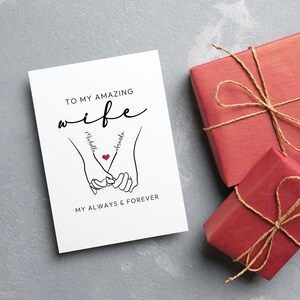 May include: A white card with black text that reads "To my amazing wife" with the names "Michelle" and "Amanda" written on the hands of a couple holding hands. The text also reads "My always & forever".
