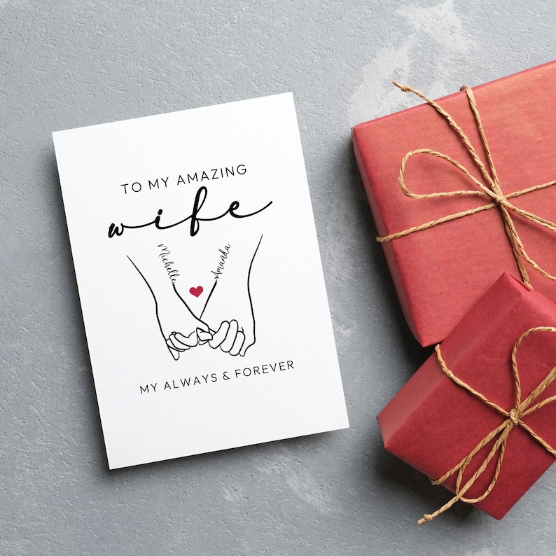 May include: A white card with black text that reads "To my amazing wife" with the names "Michelle" and "Amanda" written on the hands of a couple holding hands. The text also reads "My always & forever".