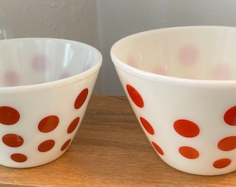 Op de afbeelding: Twee witte mengkommen met oranje stippen. De grotere kom is op de achtergrond en de kleinere kom is op de voorgrond.