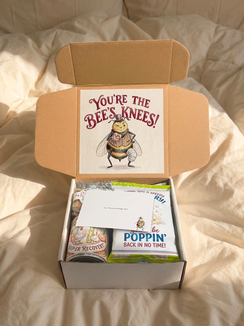 Close-up of the open knee replacement gift box with a personalized card, pun-labeled snacks, and “You’re the Bee’s Knees!” artwork inside the lid.