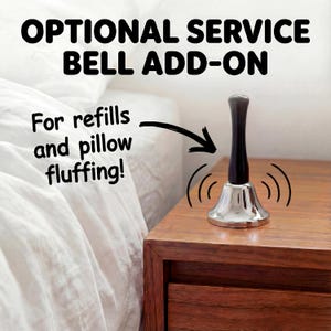 Optional silver service bell beside a bed with the message “For refills and pillow fluffing.”