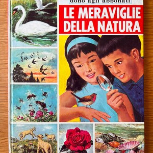 Peut inclure: Un livre vintage intitulé Corriere dei Piccoli Le Meraviglie della Natura avec une illustration de couverture montrant deux enfants utilisant une loupe pour observer un oiseau, entouré de panneaux illustrant des cygnes, oiseaux, abeilles, agneaux, une rose et des coquillages.