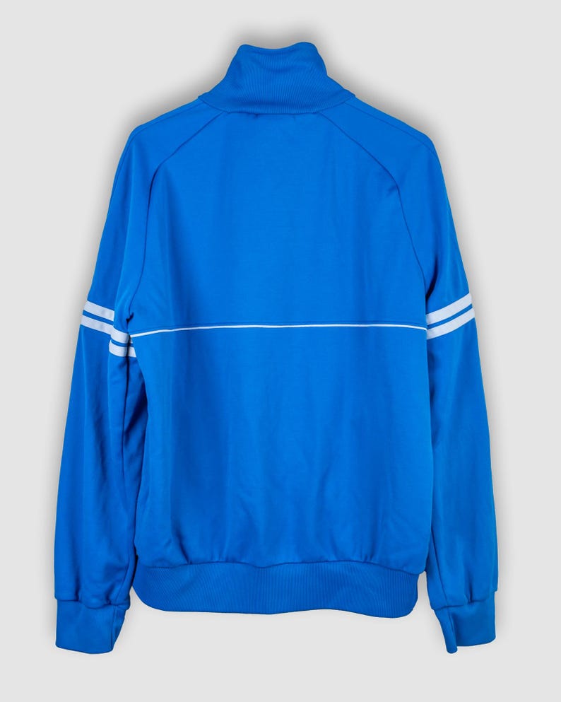 May include: A blue track jacket with white stripes on the sleeves and a white stripe across the chest.