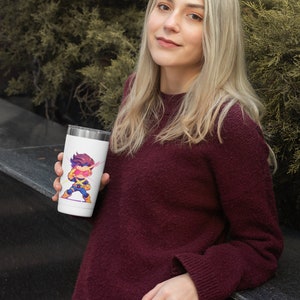 May include: A white travel mug with a cartoon image of a superhero with yellow and blue clothing and pink lightning bolts. The superhero is wearing a red mask and has a yellow lightning bolt on their chest.
