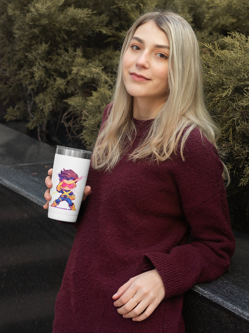 May include: A white travel mug with a cartoon image of a superhero with yellow and blue clothing and pink lightning bolts. The superhero is wearing a red mask and has a yellow lightning bolt on their chest.