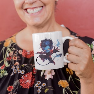 May include: White ceramic mug with a blue and red cartoon character design. The character is a blue-skinned, red-suited, and black-haired figure with a tail. The character is holding a weapon and has a cloud of smoke behind it.