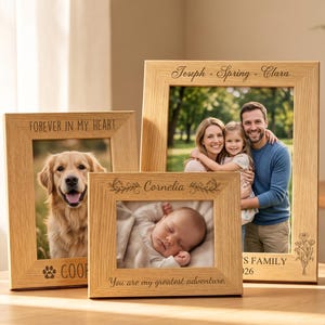 Puede incluir: Tres marcos de fotos de madera clara con texto grabado. El marco izquierdo dice FOREVER IN MY HEART y COOPER. El marco central dice Cornelia y You are my greatest adventure. El marco derecho dice Joseph + Spring + Clara y FAMILY 2026.
