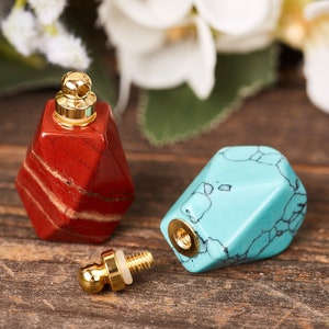 Op de afbeelding: Twee kleine, geometrisch gevormde flessen met gouden doppen. E&eacute;n fles is rood met witte strepen en de andere is blauw met witte aderen.