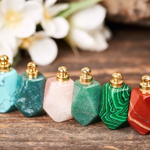 Op de afbeelding: Zes kleine, edelsteenvormige flesjes met gouden dopjes. De flesjes zijn gemaakt van turquoise, groen, roze, groen, groen en rood.