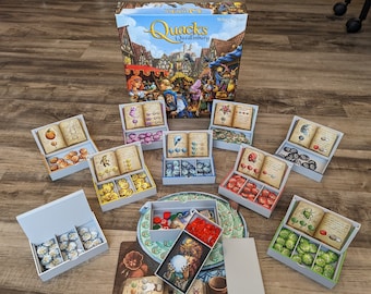 May include: A board game called "Quacks of Quedlinburg" with a colorful box and multiple game components, including a game board, dice, and tokens.