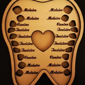 May include: A wooden tooth-shaped keepsake box with cut-out spaces for teeth. The words "Molaire", "Canine", and "Incisive" are etched into the wood. A heart shape is cut out in the center.