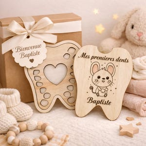 May include: Wooden tooth-shaped keepsake box with a heart cutout and a tag that says "Bienvenue Baptiste". A second wooden tooth-shaped piece features a cartoon mouse and the text "Mes premieres dents Baptiste".