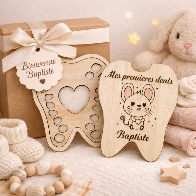 May include: Wooden tooth-shaped keepsake box with a heart cutout and a tag that says "Bienvenue Baptiste". A second wooden tooth-shaped piece features a cartoon mouse and the text "Mes premieres dents Baptiste".