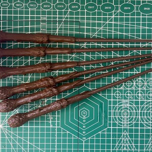 K&ouml;nnte beinhalten: F&uuml;nf braune Holzst&auml;be mit strukturierter Oberfl&auml;che, angeordnet auf einer gr&uuml;nen Schneidematte mit wei&szlig;en Markierungen.