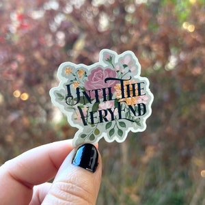 May include: A floral sticker with the text "Until the Very End" in black lettering. The sticker has a green background with pink, yellow, and white flowers.