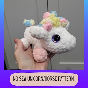 May include: A white, plush unicorn toy with pink, yellow, and blue accents. The unicorn has large, sparkly eyes and pink hooves. The text "NO SEW UNICORN/HORSE PATTERN" is displayed at the bottom of the image.