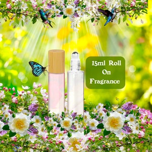 Może przedstawiać: Dwie 15 ml szklane butelki z kulką z bambusowymi nakrętkami. Butelki są wypełnione przezroczystym płynem. Butelki są otoczone białymi i r&oacute;żowymi kwiatami. Tekst "15ml Roll On Fragrance" jest widoczny na zdjęciu.