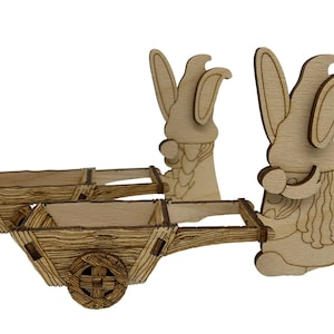 May include: A wooden decorative set featuring two gnomes with long beards and pointed hats, each holding a wheelbarrow. The wheelbarrows have a rustic design with wooden planks and a single wheel. The gnomes and wheelbarrows are made of light-coloured wood.