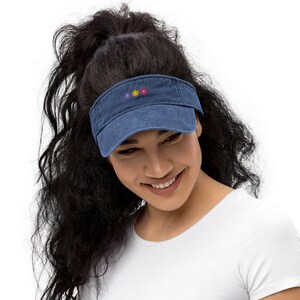 May include: A denim blue visor with a row of embroidered flowers in purple, yellow, and red.